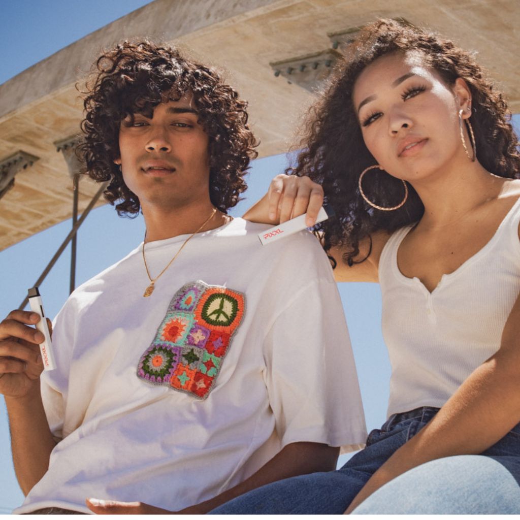 Young adults enjoying PiXXL VAPE under a sunny sky, showcasing modern style.