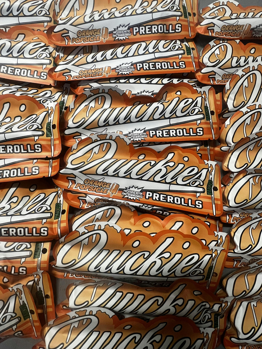 Quickies 1g infused prerolls with orange popsicle flavor, featuring vibrant orange packaging and sativa branding. High THC content for a potent smoking experience.